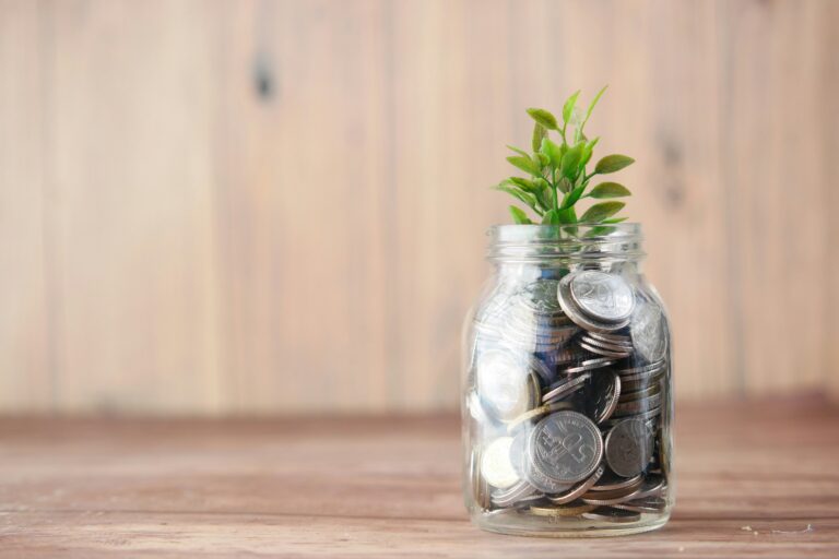 Tarro de cristal con monedas y una planta, ahorro e inversión