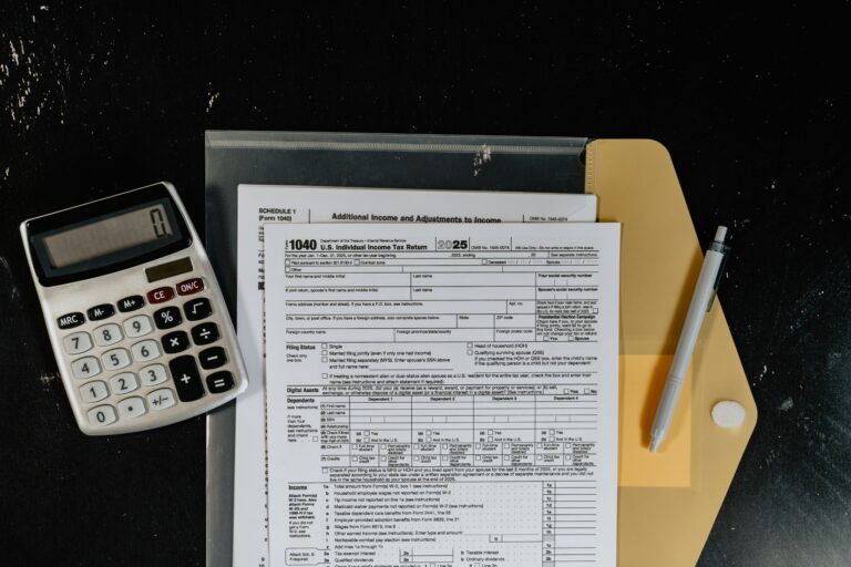 Calculadora y formularios fiscales sobre una superficie oscura
