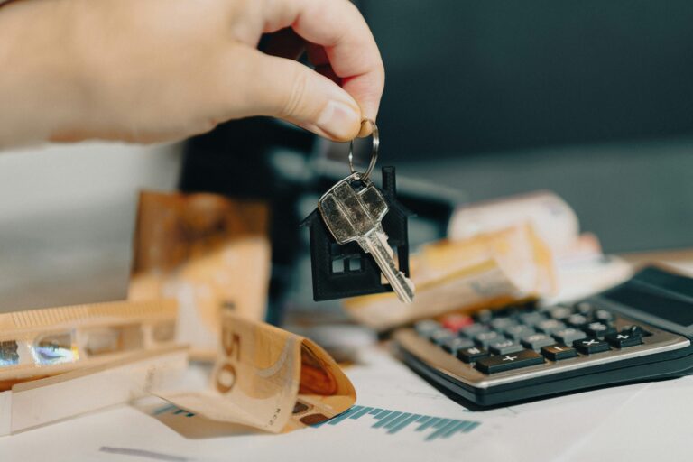Persona sosteniendo unas llaves de vivienda frente a una calculadora